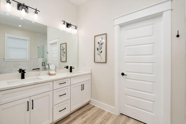 full bath with a shower stall, wood finished floors, double vanity, and baseboards