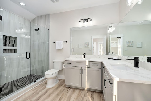 full bathroom with toilet, wood finished floors, a shower stall, double vanity, and recessed lighting