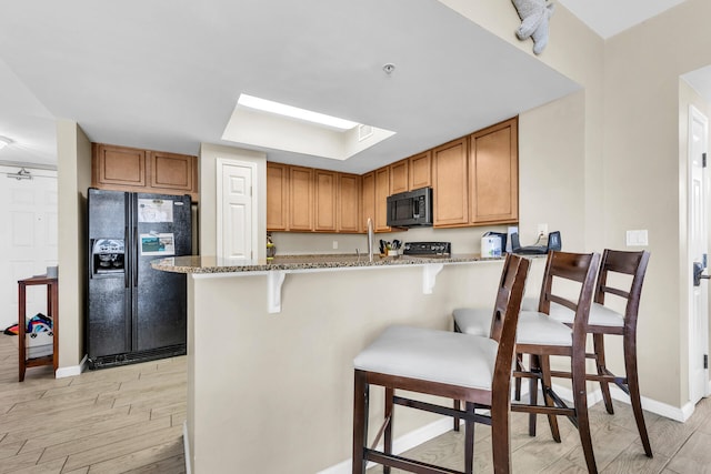 4207 Indian Bayou Trl Unit 2501, Destin, FL 32541 - kitchen with a skylight, light stone countertops, black appliances, and light wood-type flooring