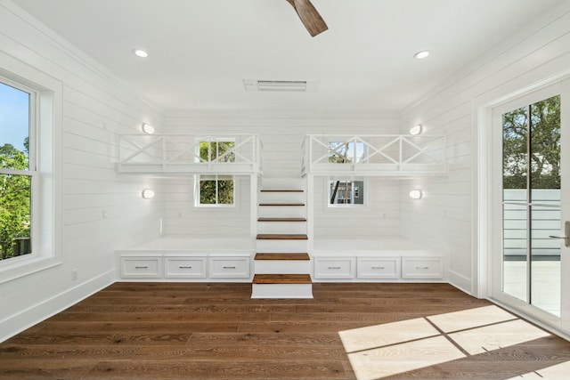 interior space featuring a ceiling fan, ornamental molding, and dark wood-style floors