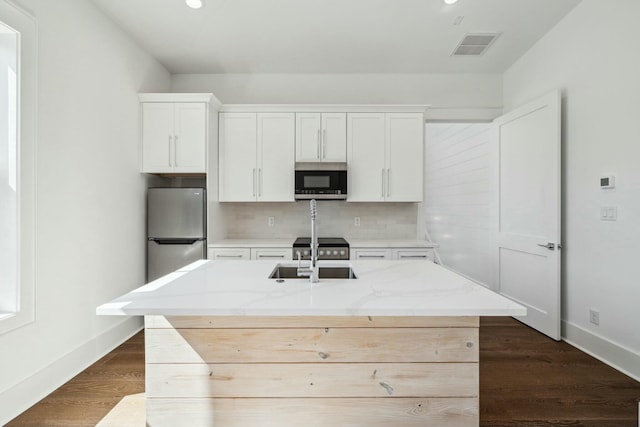 kitchen featuring a sink, tasteful backsplash, white cabinetry, baseboards, and appliances with stainless steel finishes