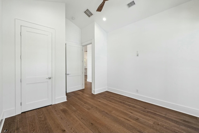 unfurnished bedroom featuring dark wood finished floors, visible vents, baseboards, and vaulted ceiling