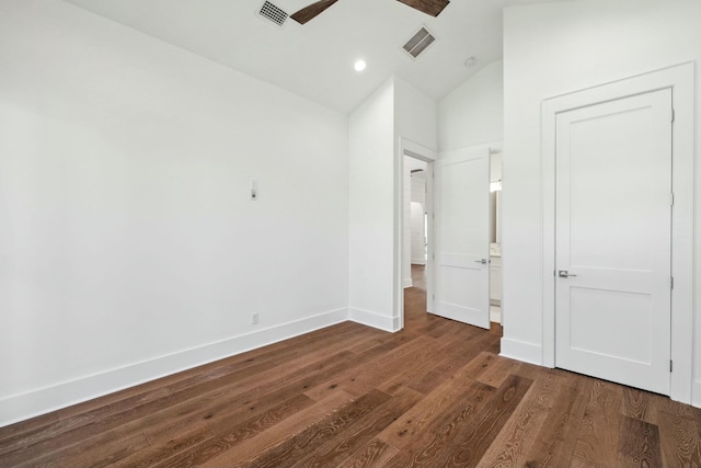 unfurnished bedroom featuring dark wood-type flooring, visible vents, lofted ceiling, and baseboards