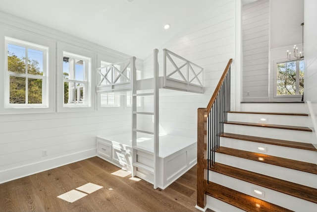 stairway with lofted ceiling, a chandelier, wood finished floors, and baseboards