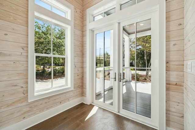 doorway with wood walls, dark wood-style flooring, and french doors