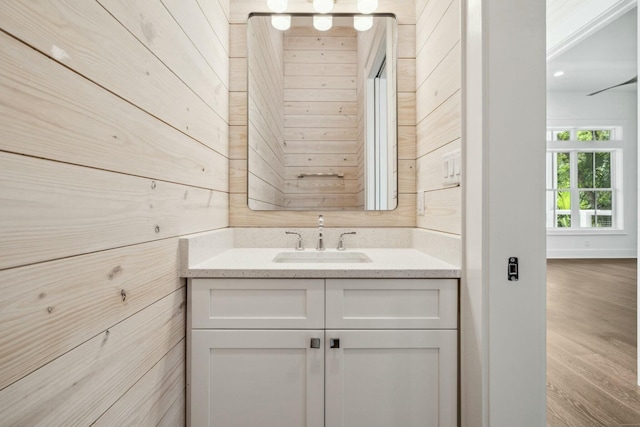 bathroom with wood walls, wood finished floors, and vanity