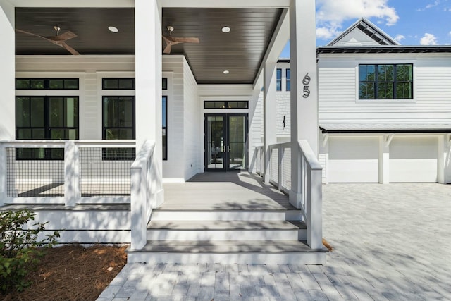 doorway to property featuring a porch, an attached garage, and french doors