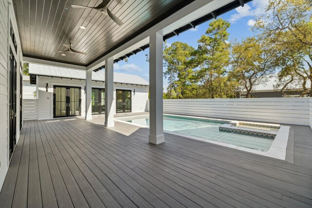 wooden deck with a jacuzzi, fence, a ceiling fan, and an outdoor pool