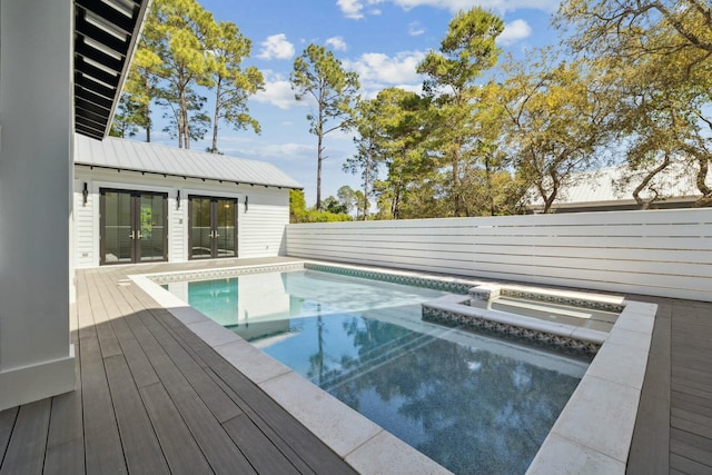 outdoor pool with an in ground hot tub, a wooden deck, and a fenced backyard