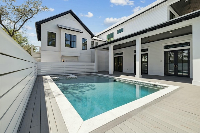 view of swimming pool with french doors, a wooden deck, and a pool with connected hot tub