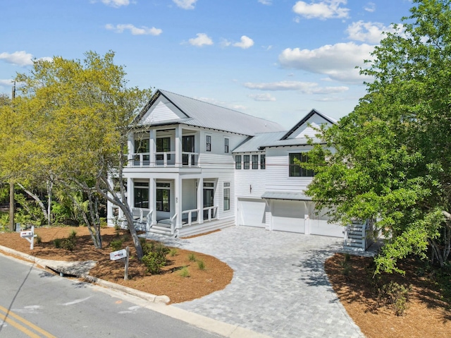 view of front of property with a porch, decorative driveway, metal roof, a garage, and a balcony