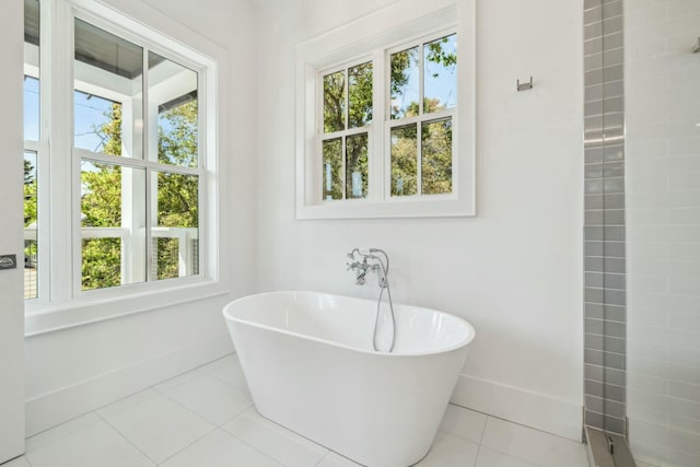 bathroom with a soaking tub, plenty of natural light, tile patterned flooring, and baseboards