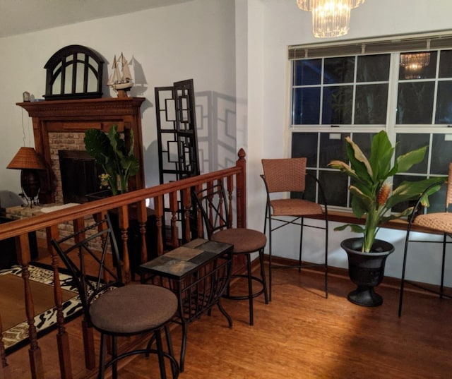 interior space featuring a brick fireplace, wood finished floors, and a notable chandelier