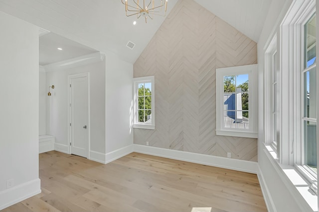 interior space featuring light wood finished floors, a chandelier, visible vents, baseboards, and lofted ceiling