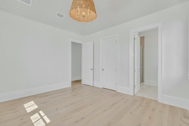 unfurnished bedroom with a chandelier, visible vents, light wood-style floors, and baseboards