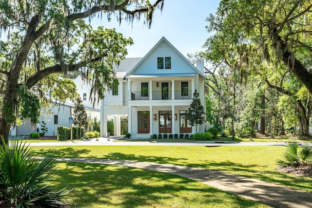 neoclassical / greek revival house with covered porch, a front lawn, french doors, and a balcony