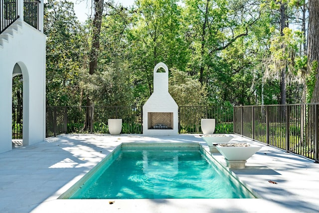 view of swimming pool featuring fence, a fenced in pool, exterior fireplace, and a patio area