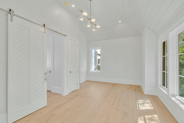 unfurnished bedroom with wooden ceiling, vaulted ceiling, a barn door, and light wood-style floors