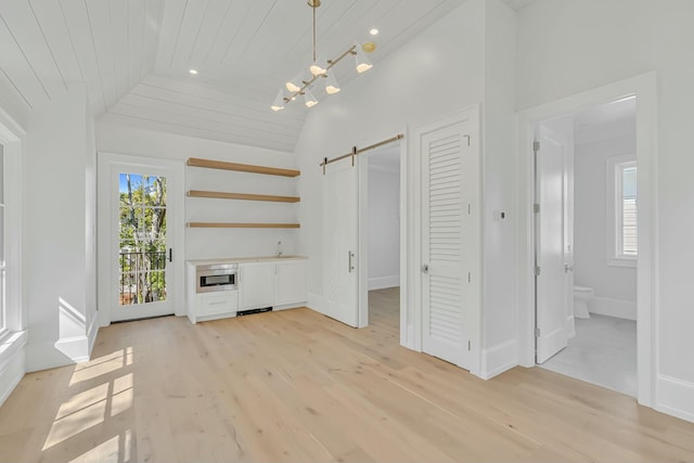 unfurnished dining area featuring wooden ceiling, a barn door, light wood-style floors, vaulted ceiling, and baseboards
