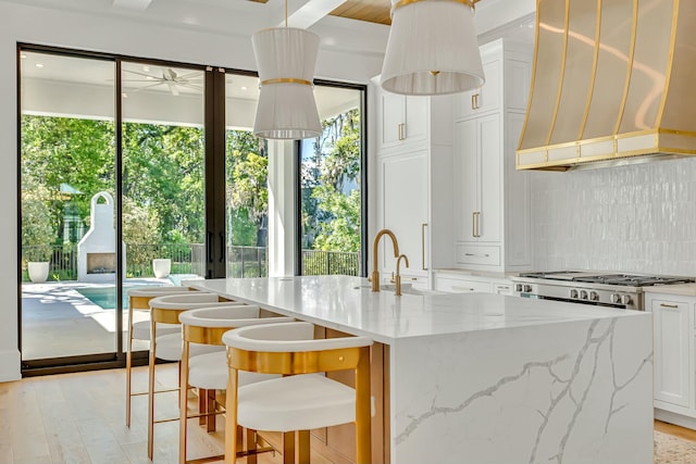 kitchen featuring wall chimney range hood, tasteful backsplash, plenty of natural light, and white cabinets