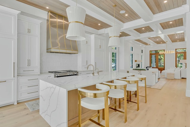 kitchen with recessed lighting, a large island with sink, backsplash, light wood-type flooring, and open floor plan