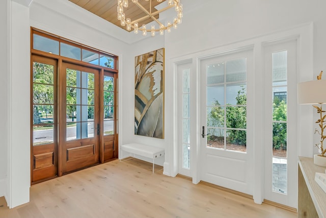 doorway with light wood-type flooring, an inviting chandelier, and wooden ceiling
