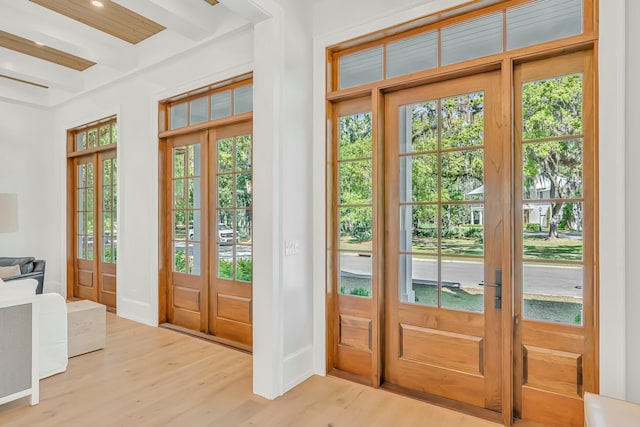 entryway featuring beam ceiling, french doors, and light wood-style flooring