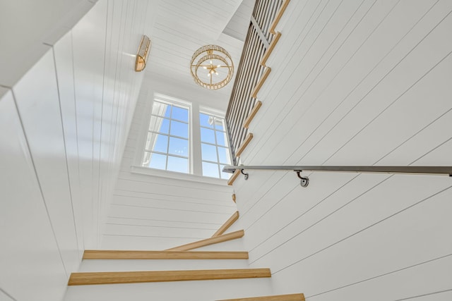 stairway with wooden walls and a chandelier