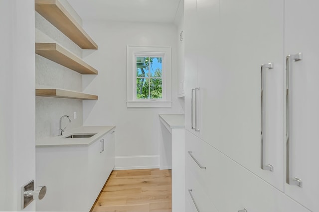 laundry room featuring a sink, light wood-style flooring, and baseboards
