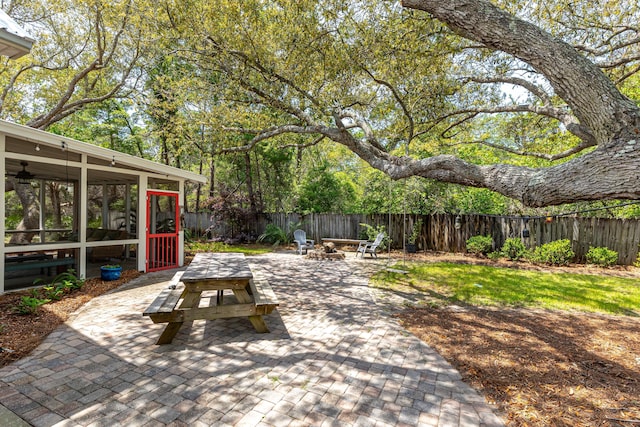 view of patio featuring a fire pit, a sunroom, and a fenced backyard