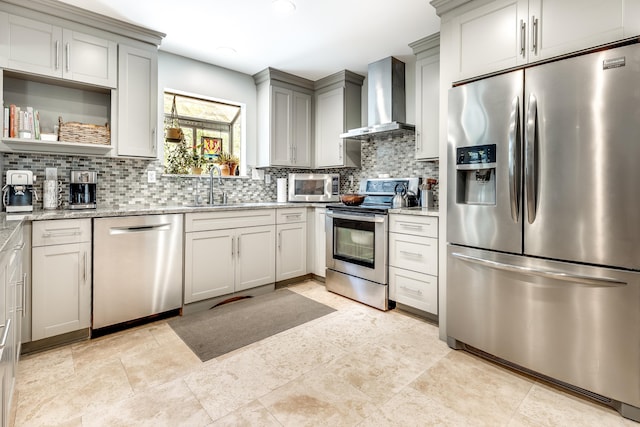 kitchen with tasteful backsplash, wall chimney exhaust hood, appliances with stainless steel finishes, and a sink