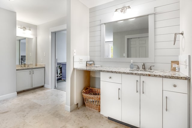 full bath with two vanities, a sink, and baseboards