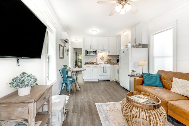 living area featuring ceiling fan, a wall unit AC, and light wood-style flooring