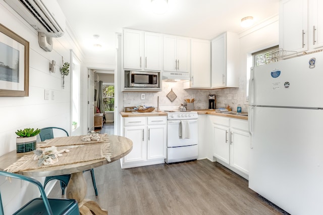 kitchen featuring light wood finished floors, a wealth of natural light, under cabinet range hood, and white appliances