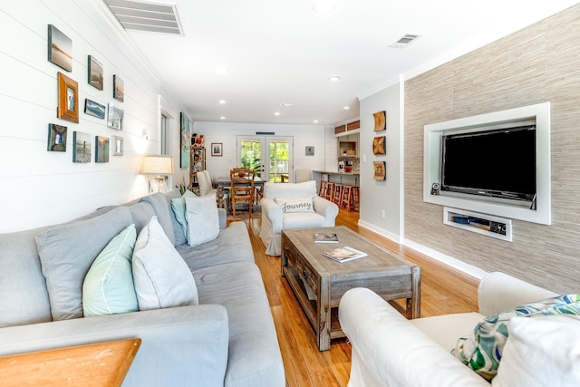 living room featuring visible vents, light wood-type flooring, and ornamental molding