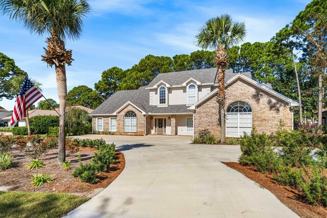 traditional-style home with brick siding, a shingled roof, and driveway