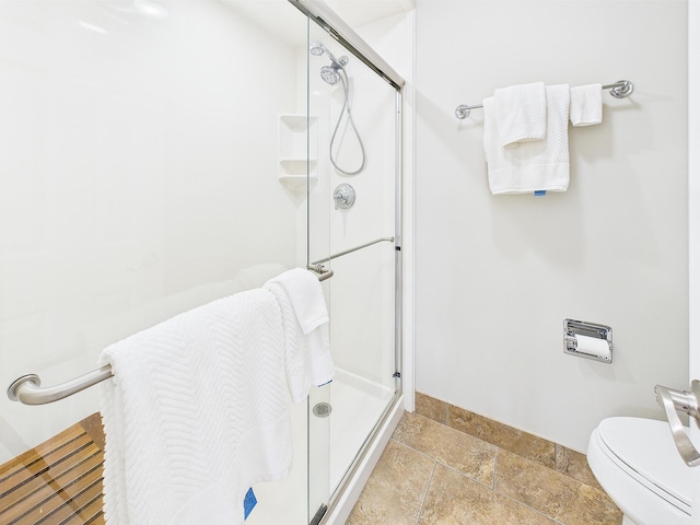 210 Southlake Ct Unit 210, Niceville, FL 32578 - bathroom featuring a stall shower, baseboards, stone tile floors, and toilet