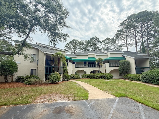 210 Southlake Ct Unit 210, Niceville, FL 32578 - view of front of house with stucco siding, a front lawn, a balcony, and uncovered parking