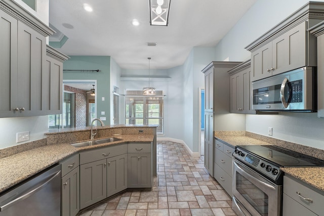 7008 Turnberry Cir, Navarre, FL 32566 - kitchen with a sink, a peninsula, light stone counters, gray cabinetry, and appliances with stainless steel finishes