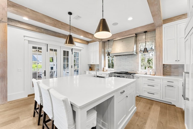 98 Compass Point Way, Inlet Beach, FL 32461 - kitchen with custom range hood, beam ceiling, tasteful backsplash, a sink, and light wood-style floors