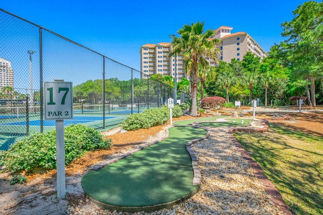 view of home's community with a tennis court and fence
