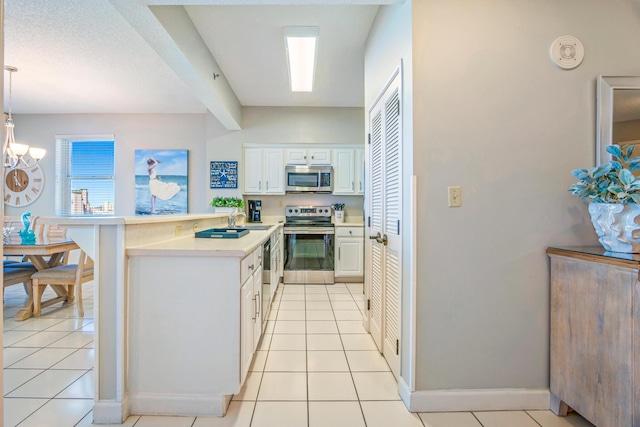 kitchen with light tile patterned flooring, appliances with stainless steel finishes, a sink, light countertops, and a peninsula