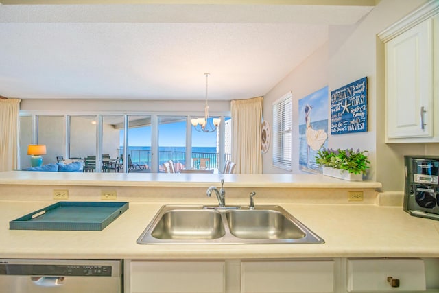 kitchen featuring light countertops, white cabinets, a sink, dishwasher, and a notable chandelier