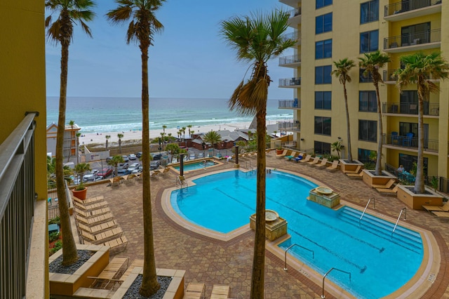 pool featuring a view of the beach, a community hot tub, and a water view