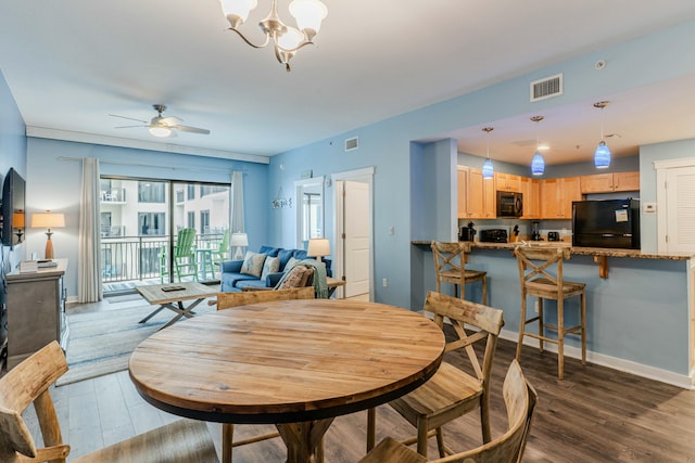 dining space with dark wood-style floors, visible vents, and ceiling fan with notable chandelier