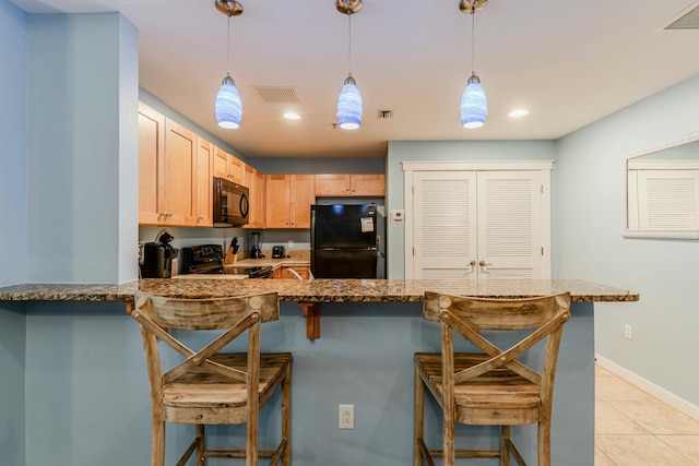 kitchen with visible vents, stone countertops, black appliances, a kitchen bar, and a peninsula