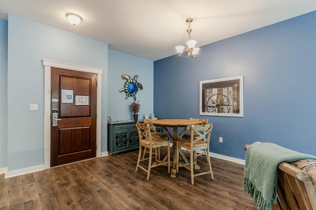 dining space featuring dark wood-style flooring, a notable chandelier, and baseboards