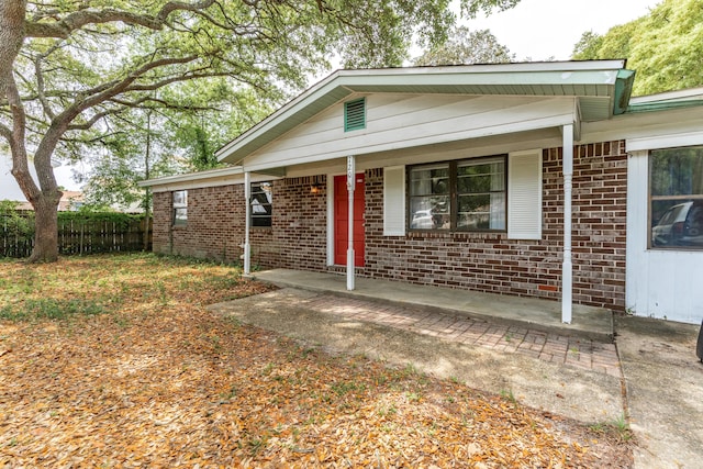 single story home featuring fence, covered porch, and brick siding