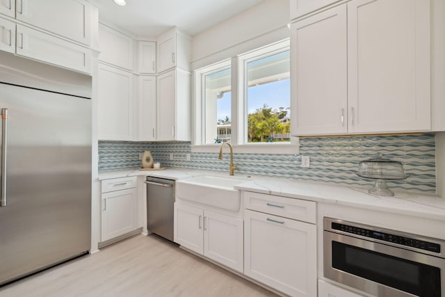 144 Dalton Dr, Santa Rosa Beach, FL 32459 - kitchen featuring light stone countertops, built in appliances, backsplash, a sink, and light wood-type flooring