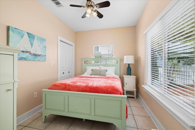 bedroom featuring visible vents, a closet, light tile patterned flooring, baseboards, and a ceiling fan